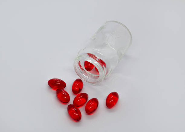 istock Red capsules scattered from a jar on a white background 2187864084