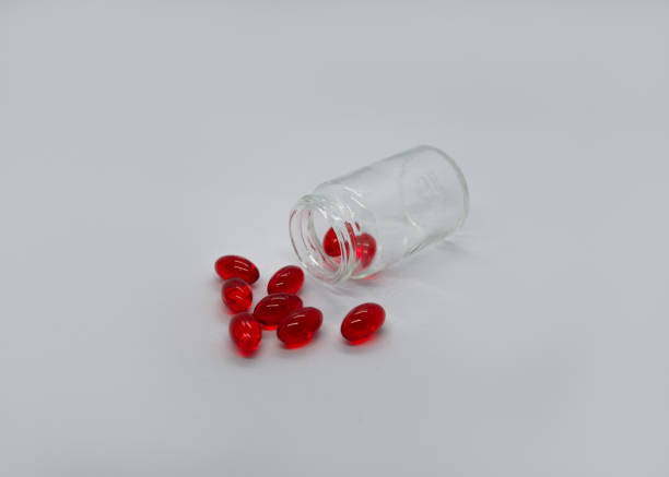 istock Red capsules scattered from a jar on a white background 2187864113