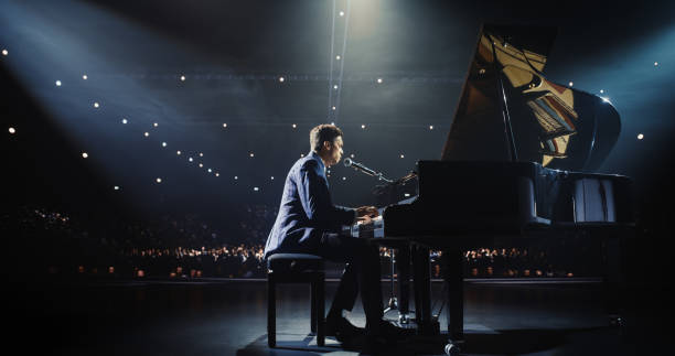 istock Young Pianist Playing and Singing, Performing an Experimental Solo Compositions on Stage. Grand Piano Resounds With Rich, Melodic Tones of a Romantic Ballad, Pianist Leaving the Audience in Awe 2187864248