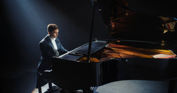 istock Masterful Music Artist Performing on a Dark Empty Stage, His Hands Moving Effortlessly Over the Grand Piano. Sophisticated Musician Brings a Dramatic and Emotional Composition to Life 2187864315