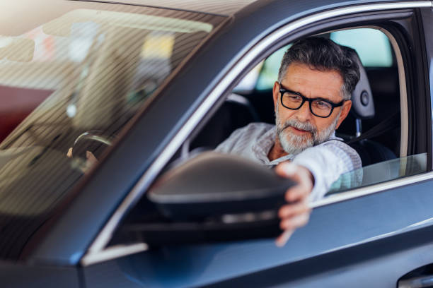 istock Senior Man Driving Car and Adjusting Rearview Mirror 2187867842