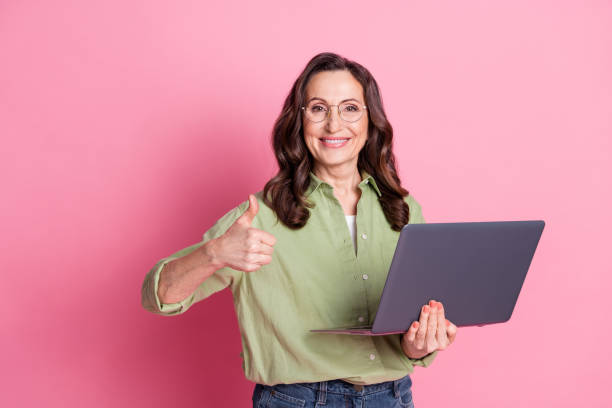 istock Photo of worker experienced programmer retired lady in khaki shirt hold computer enjoy her new job isolated on pink color background 2187869621