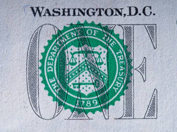 Close-up macro image of the U.S. Treasury seal overlaid on ornate printed text and engraved patterns on a banknote. The textured paper surface, layered ink colors, and intricate linework highlight authenticity and the detailed craftsmanship of traditional currency design.