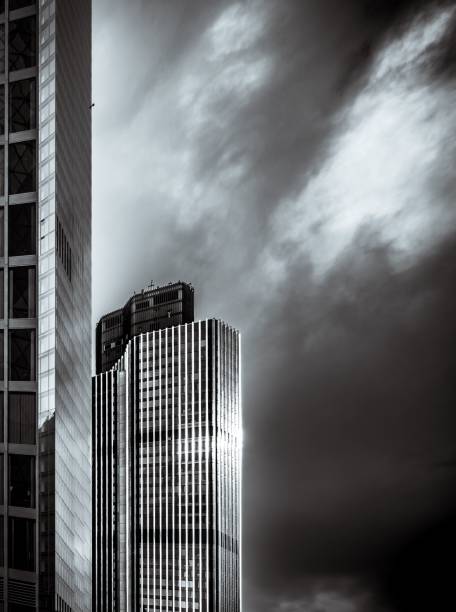A modern skyscraper with reflective glass panels under dramatic cloudy skies in London