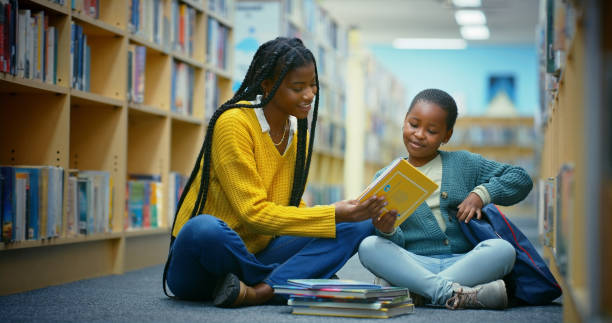 istock Library, child and teacher reading book for education, learning and knowledge for storytelling. Educator, black woman and girl on floor for fun, fantasy stories and language development or relaxing 2187876906