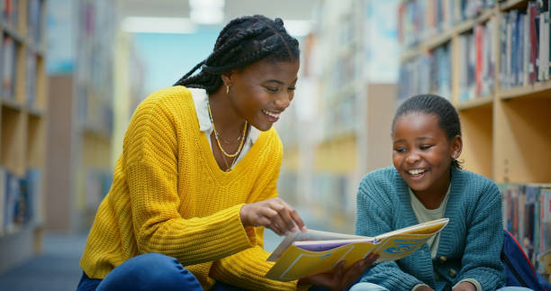 istock Library, child and black woman reading book for education, learning and knowledge for storytelling. Educator, teacher and girl on floor for fun, fantasy stories and language development or relaxing 2187876916
