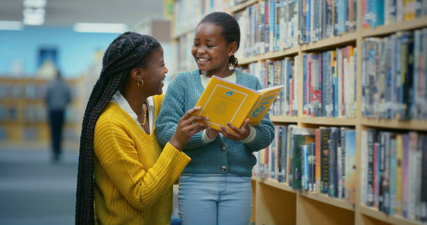 istock Library, child and teacher help reading book for education, learning and knowledge for storytelling and language. Educator, black woman and girl for fun, fantasy stories and development or relaxing 2187876929