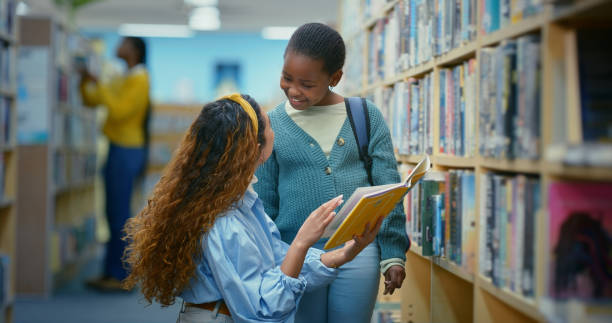 istock Happy kid, library and librarian reading book to student for help, learning or show literature at school. Child, woman or education at bookshelf for knowledge, study advice or support for development 2187876938