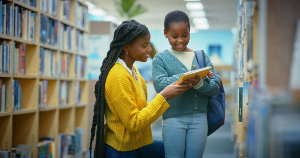 istock Library, child and black woman help reading book for education, learning and knowledge for storytelling and language. Educator, teacher and girl for fun, fantasy stories and development or relaxing 2187876949