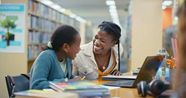 istock Woman, child and laughing for education in library with learning support, language development and advice. Tutor, student and notebook with laptop for studying comedy, assessment meme and funny joke 2187877044