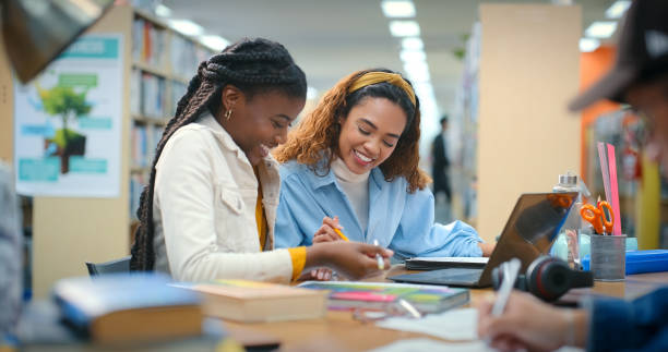 studenten, frauen oder lesepapier in der bibliothek für wissen, informationen oder college-stipendium. laptop, teamarbeit oder glückliche menschen, die dokumente für die forschung, schule oder hilfe für tests in der universität lernen - universitätsstudent stock-fotos und bilder