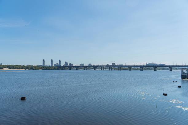 View of harbor with a small structure, bridge, urban skyline, and river during daylight