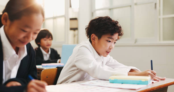 istock Japanese, children and writing for education in classroom, creative learning and art assessment of growth. Students, stationery and drawing sketch with studying, knowledge and project lesson in Japan 2187885984