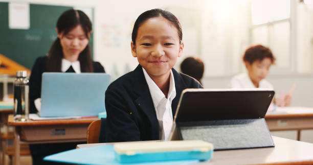 istock Boy, tablet and portrait in classroom with smile, education or info on web with research for project. School kids, learner and digital touchscreen for assessment, test and pride at academy in Japan 2187885988