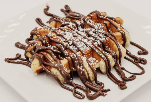 istock Belgian waffles with chocolate syrup on a white plate closeup 2187886361