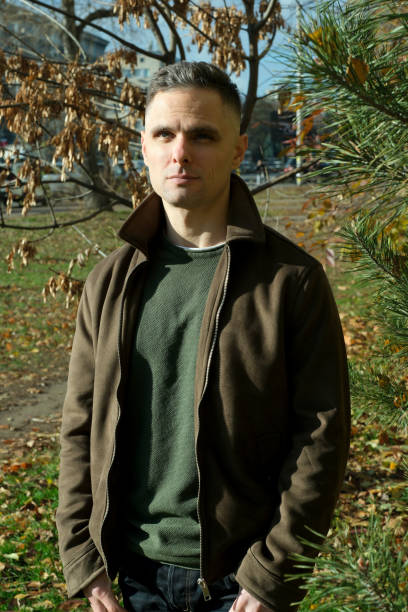istock Man standing confidently outdoors in a vibrant autumn park setting 2187889816