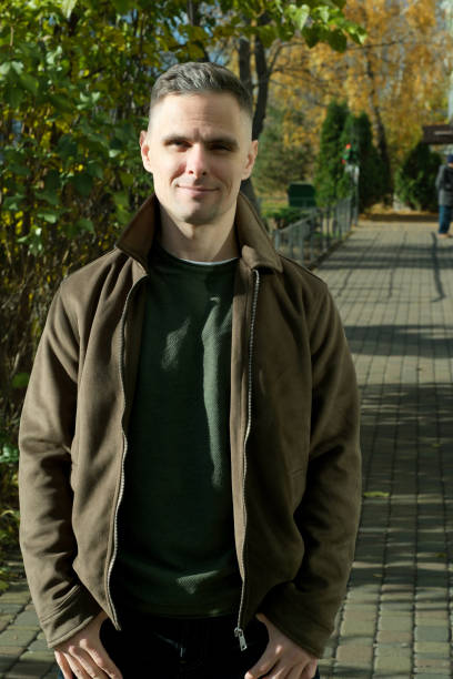 istock Confident man in brown jacket strolls along a peaceful autumn path 2187889976