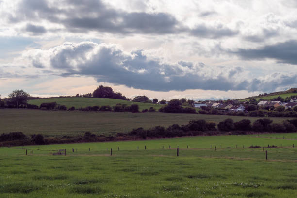 istock A village among green fields and trees under a cloudy evening sky, County Cork. Rustic Irish landscape in summer, European village. Green grass field under cloudy sky 2187890452