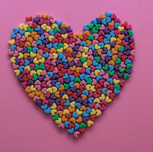 small multi colored hearts forming a big heart on pink background