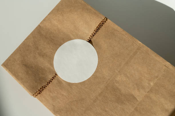 Close-up shot of a brown paper bag with a blank white label, presented on a neutral background for mockup purposes
