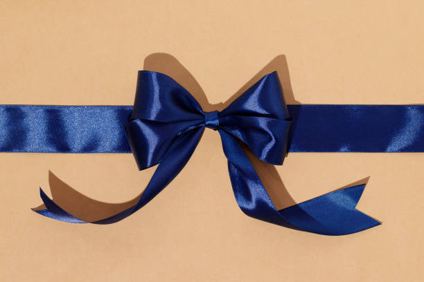 istock Blue gift ribbon and bow on craft wrapping paper 2187895360