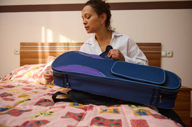 istock Woman preparing to pack violin case on a colorful patterned bed 2187897954