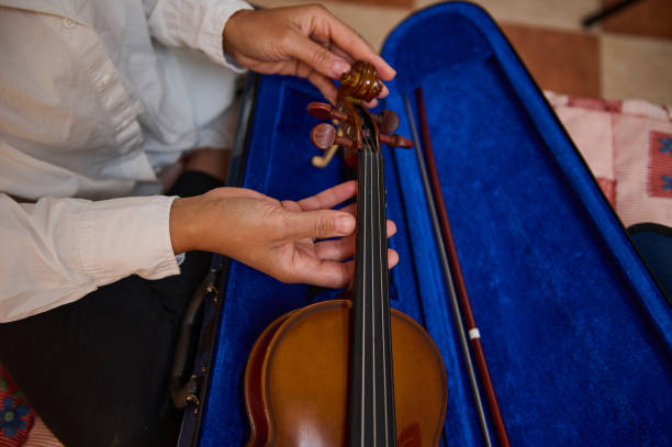 istock Close-up of hands tuning a violin with bow in blue case 2187897961