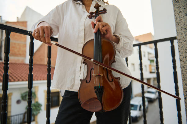 istock Person playing violin on a balcony with city backdrop 2187897964