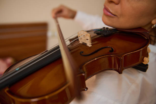 istock Close-up of a woman playing a violin with focused expression 2187898017