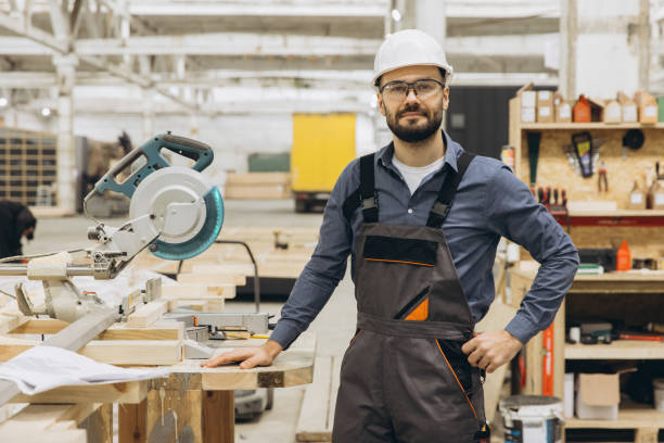 istock Carpenter standing next to circular saw and wooden planks in workshop 2187900988