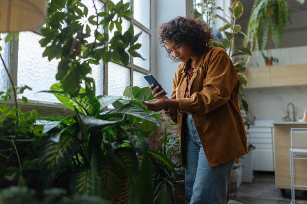 istock Young woman checking her houseplants with a smartphone app 2187901961