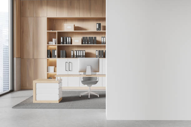 istock Modern office interior featuring wooden shelves with binders and a computer desk. There's an empty white wall on the right side, offering copy space. Concept of workspace design. 3D Rendering 2187903393