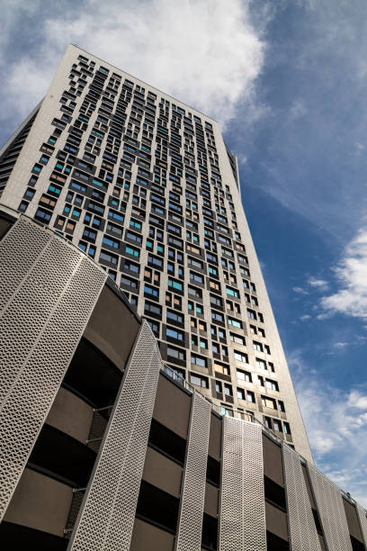 istock A modern high-rise building with a unique geometric facade, viewed from a low angle against a partly cloudy blue sky. The windows reflect sunlight, emphasizing its contemporary design. 2187906178