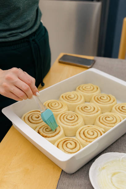 istock A young girl greases raw cinnabons in a baking dish on the table. 2187911727