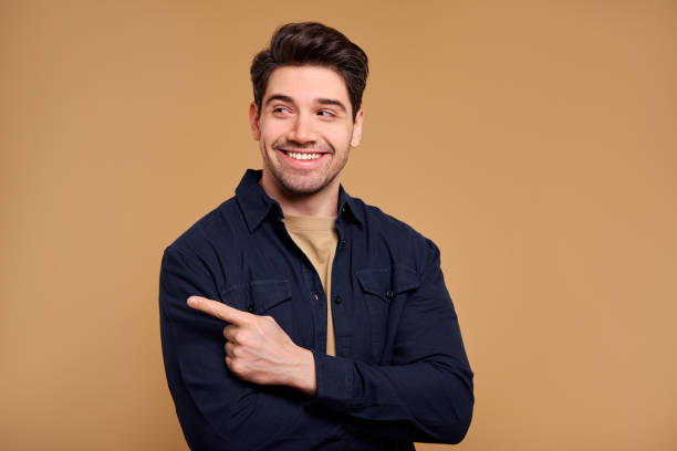 istock A Cheerful Smiling Man is Confidently Pointing Against a Vibrant and Warm Background 2187915125