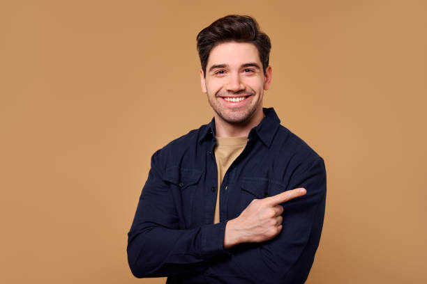 A Cheerful Smiling Man is Confidently Pointing Against a Vibrant and Warm Background