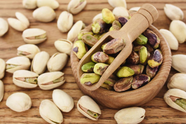 istock Fresh green pistachios in spoon on shelled pistachio nuts background 2187915582