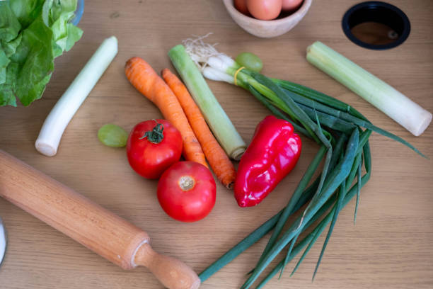 Various vegetables are laid out on the table: celery, carrot, cucumber, tomato, potato, mushrooms, onion, garlic, pepper.