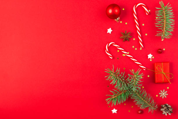 istock Christmas composition with fir branches, gift boxes, red decorations, candy and pine cones isolated on red background. Flat lay. Happy New Year and winter holidays background. Top view 2187921293