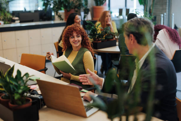 istock Businesspeople discussing in modern green office with plants 2187921927