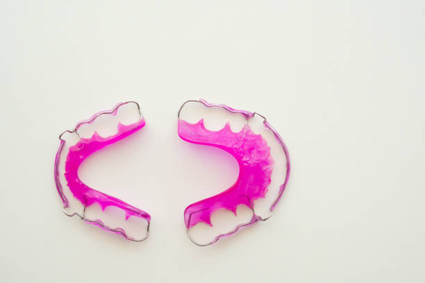Pink acrylic dental retainer on white background