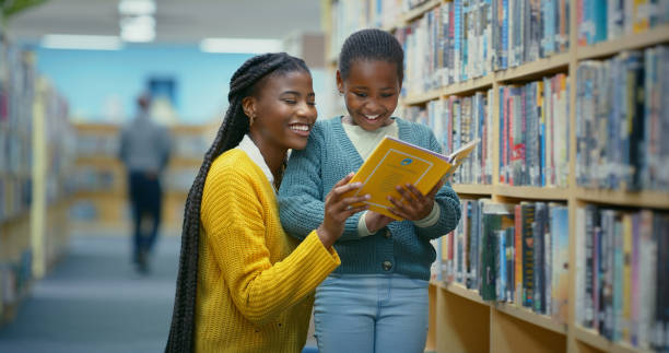 istock Library, girl and teacher help reading book for education, learning and knowledge for storytelling and language. Educator, black woman and kid for fun, fantasy stories and development or relaxing 2187942630