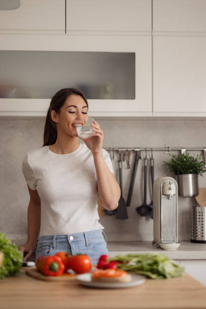 istock Happy woman drinking fresh water in the kitchen. 2187944651