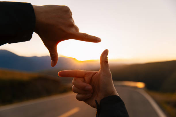 Hands in the shape of picture frame against the sunset