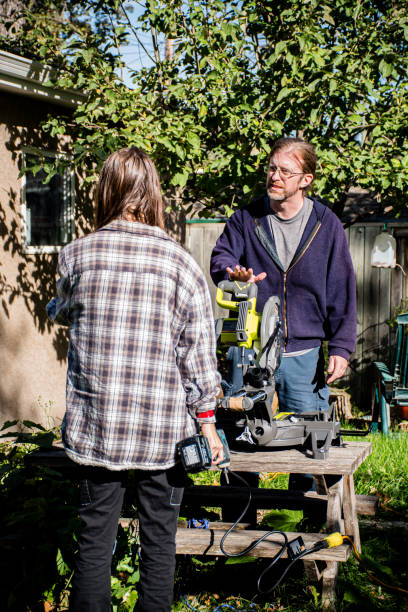 istock Father Teaching Trans Son to Use Miter Saw in Backyard Workshop 2187953268