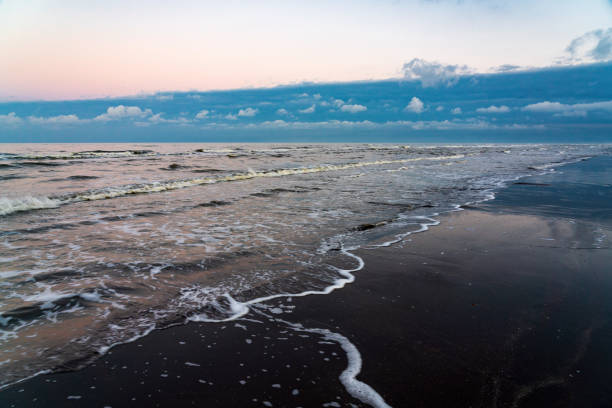 Sandy ocean shore after sunset with dark thunderclouds in the distance