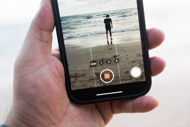 istock Shooting video with phone. Shooting man walking at the beach 2187963676
