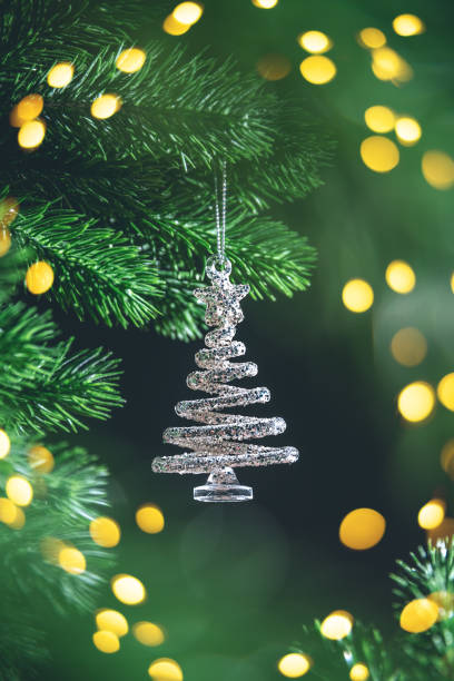 istock Silver spiral christmas tree ornament hanging from a green branch on dark background, creating a festive and magical atmosphere with copy space 2187964303