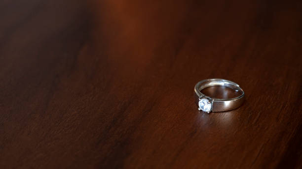 istock A platinum ring with diamonds rests on a luxurious wooden background. 2187966658