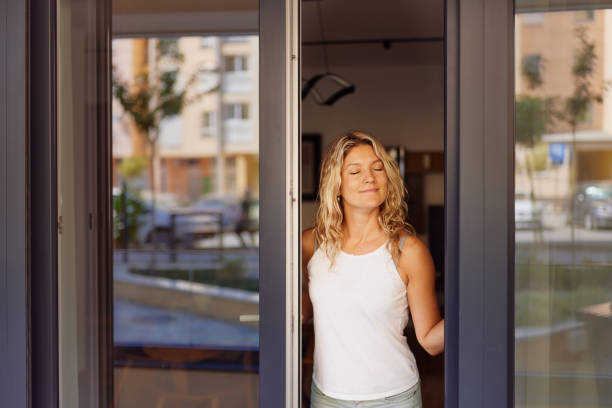 istock Smiling woman opening sliding doors on a patio. 2187967795